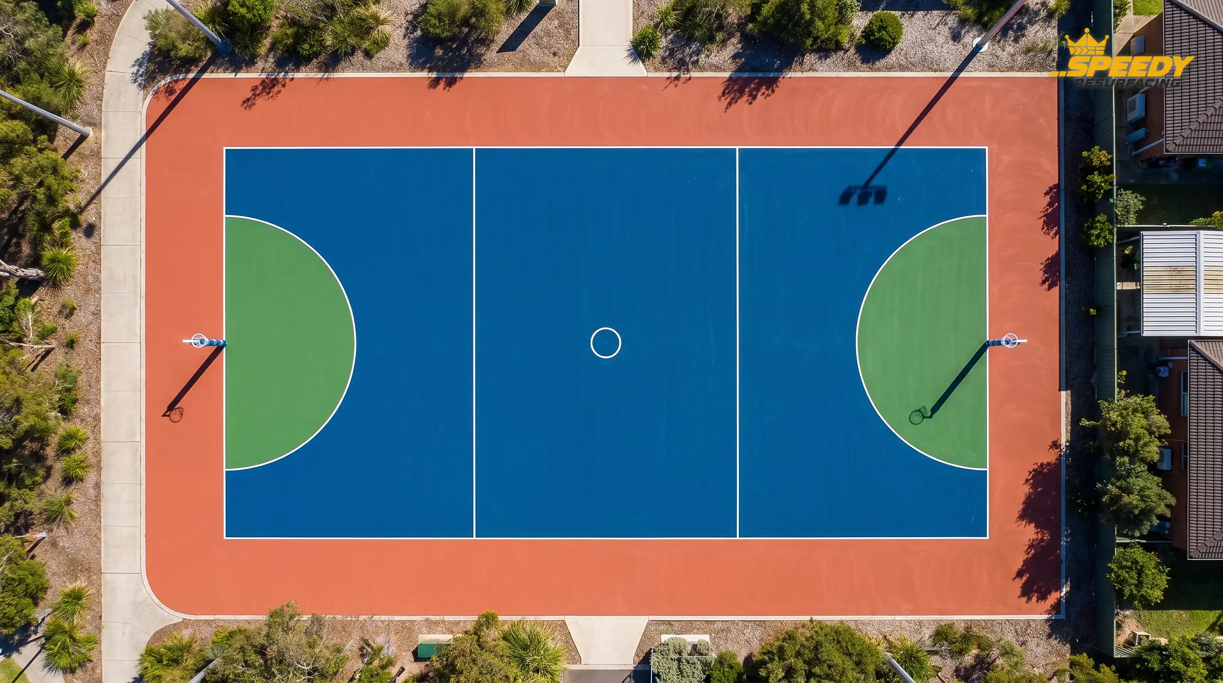 Custom colour restoration: deep blue court body, terracotta surround, solid green goal circles — UV-stable pigments built for the Australian sun.