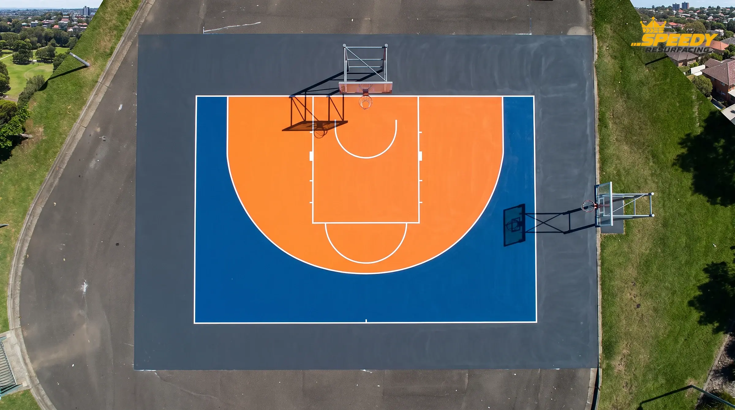 Colour-zone resurfacing — orange key, royal-blue court and charcoal apron — gives a court instant visual clarity and a custom, professional finish.