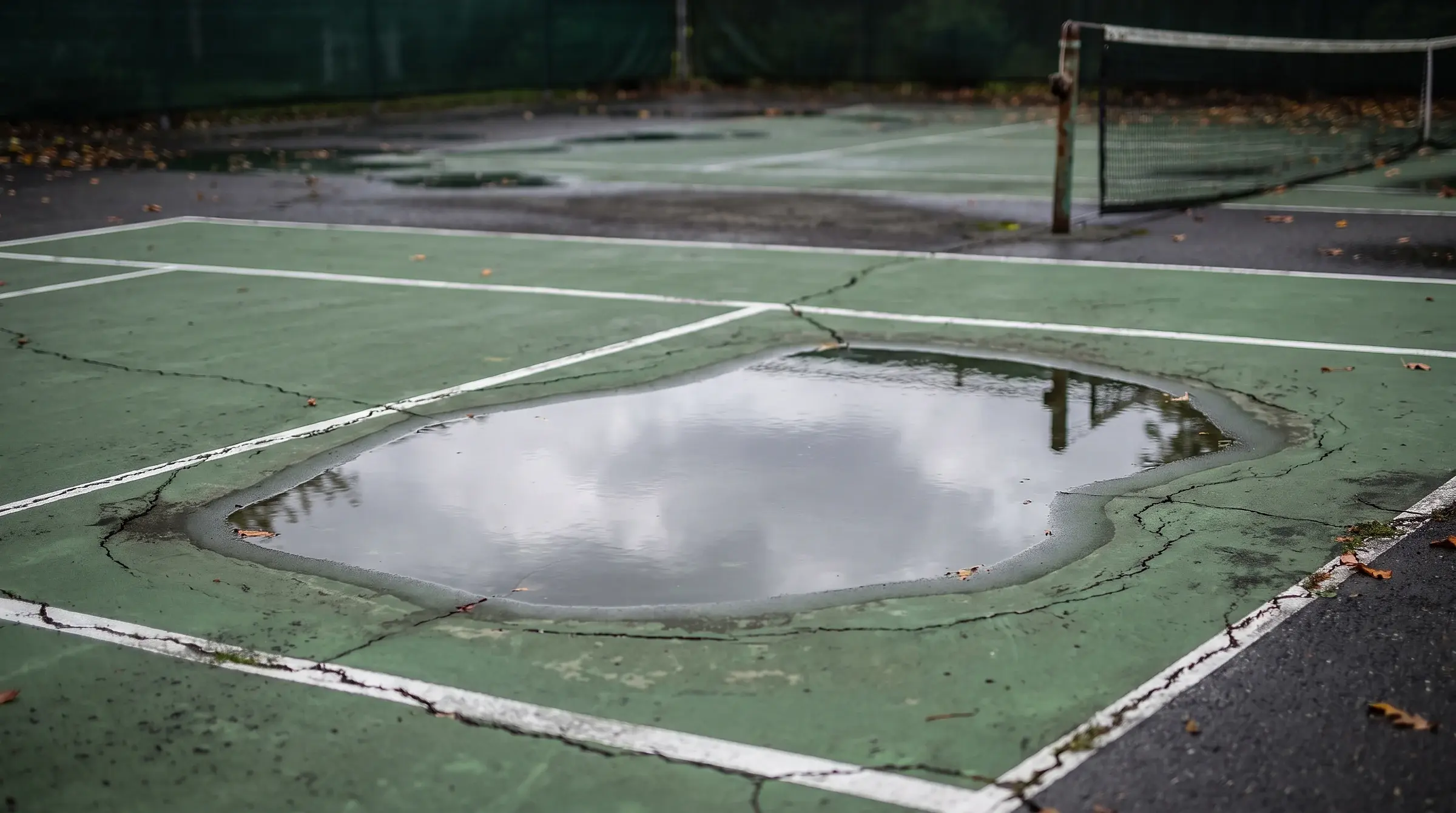 A classic 'birdbath' — the low spot still holding water hours after rain is exactly where the binder fails first.