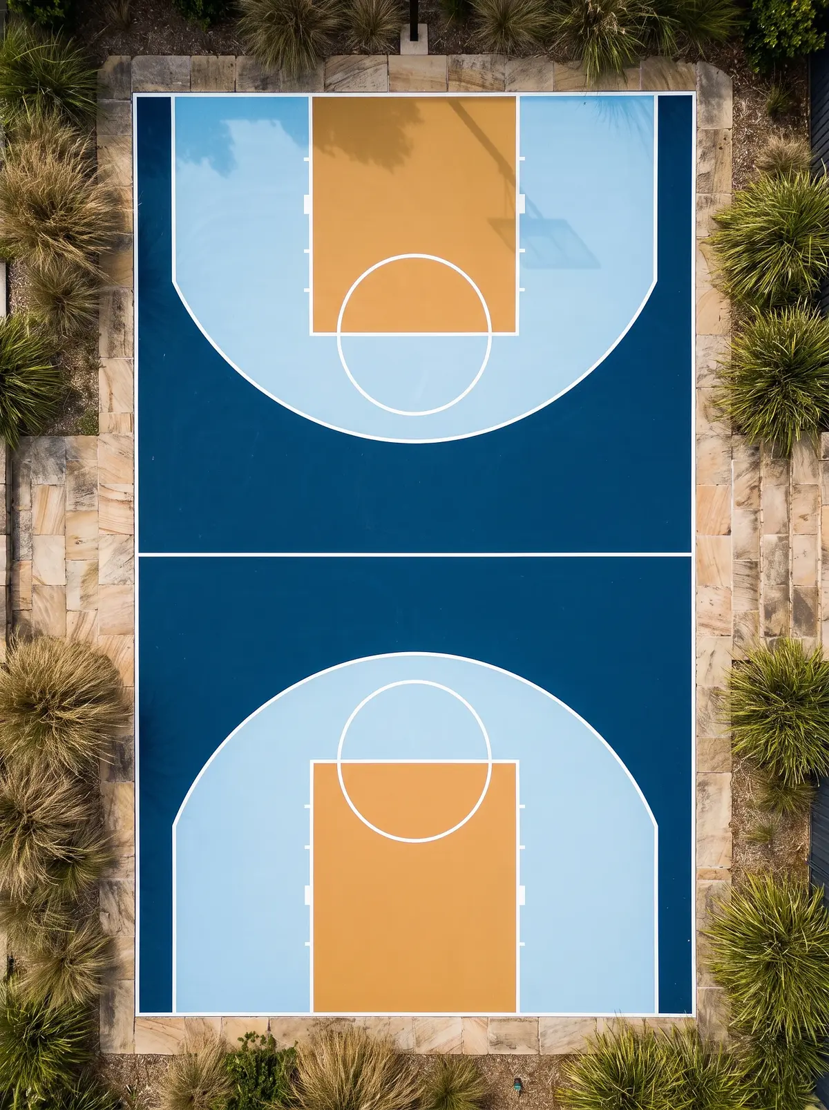 Aerial view of a Coastal Luxe residential multi-sport court — pacific navy, light sky-blue keyways and ochre key zones