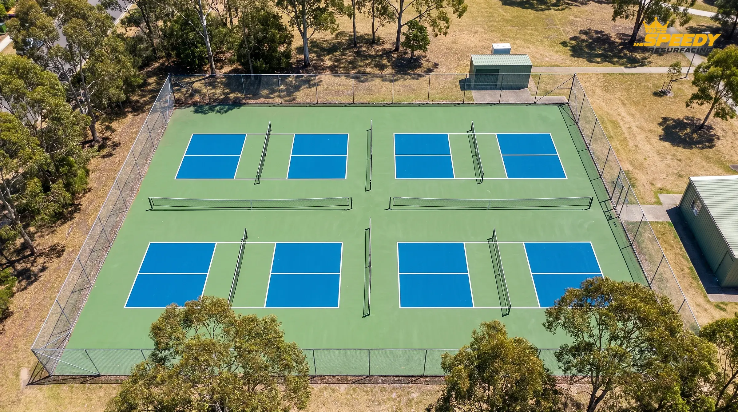 One tennis court, four pickleball courts: portable nets, retained perimeter fencing and clear movement channels between adjacent courts.