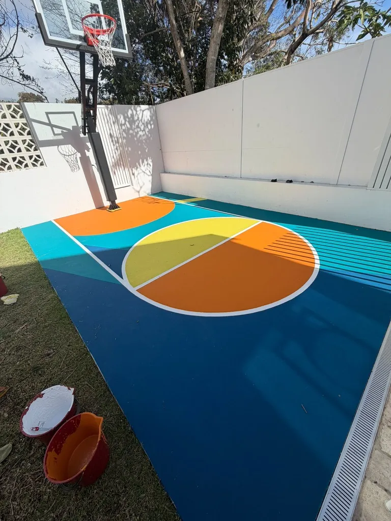 Bold orange key under the hoop on a teal 5-colour backyard basketball court in Sydney