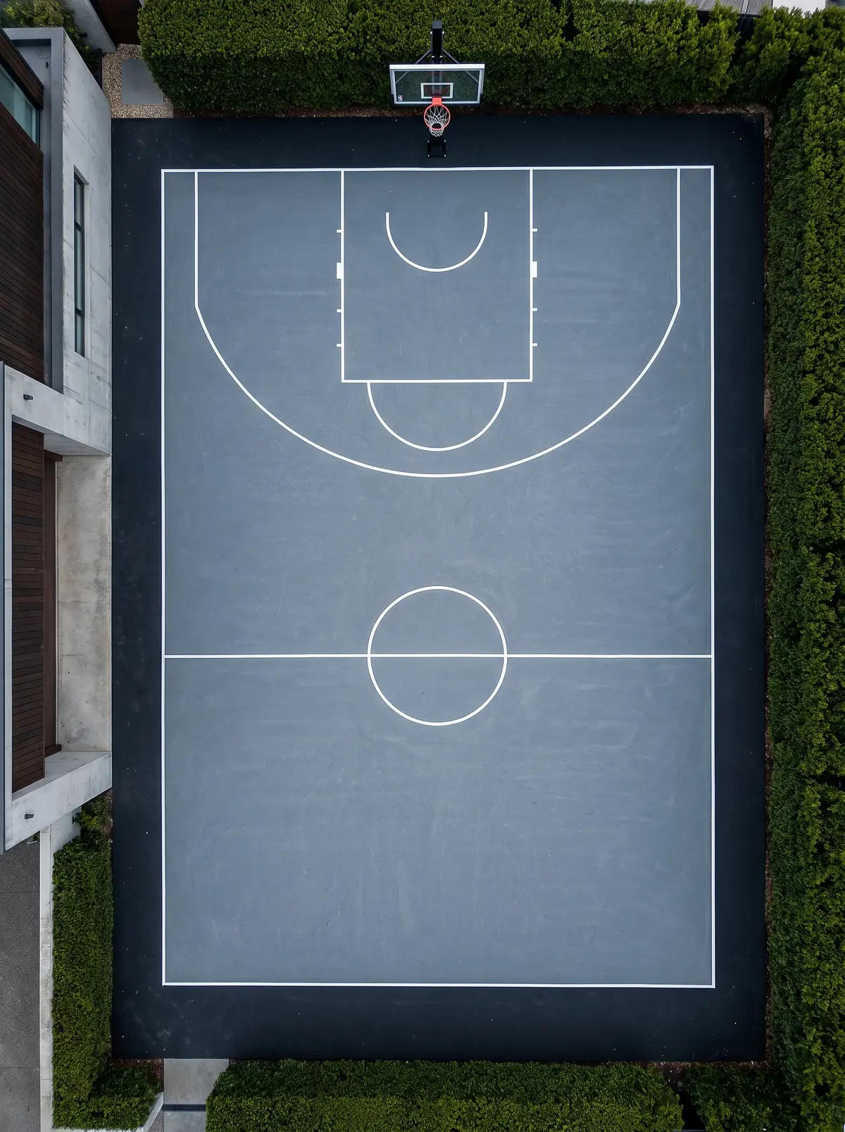 Aerial view of a Modern Minimalist residential basketball court — slate grey surface, obsidian border, arctic white lines