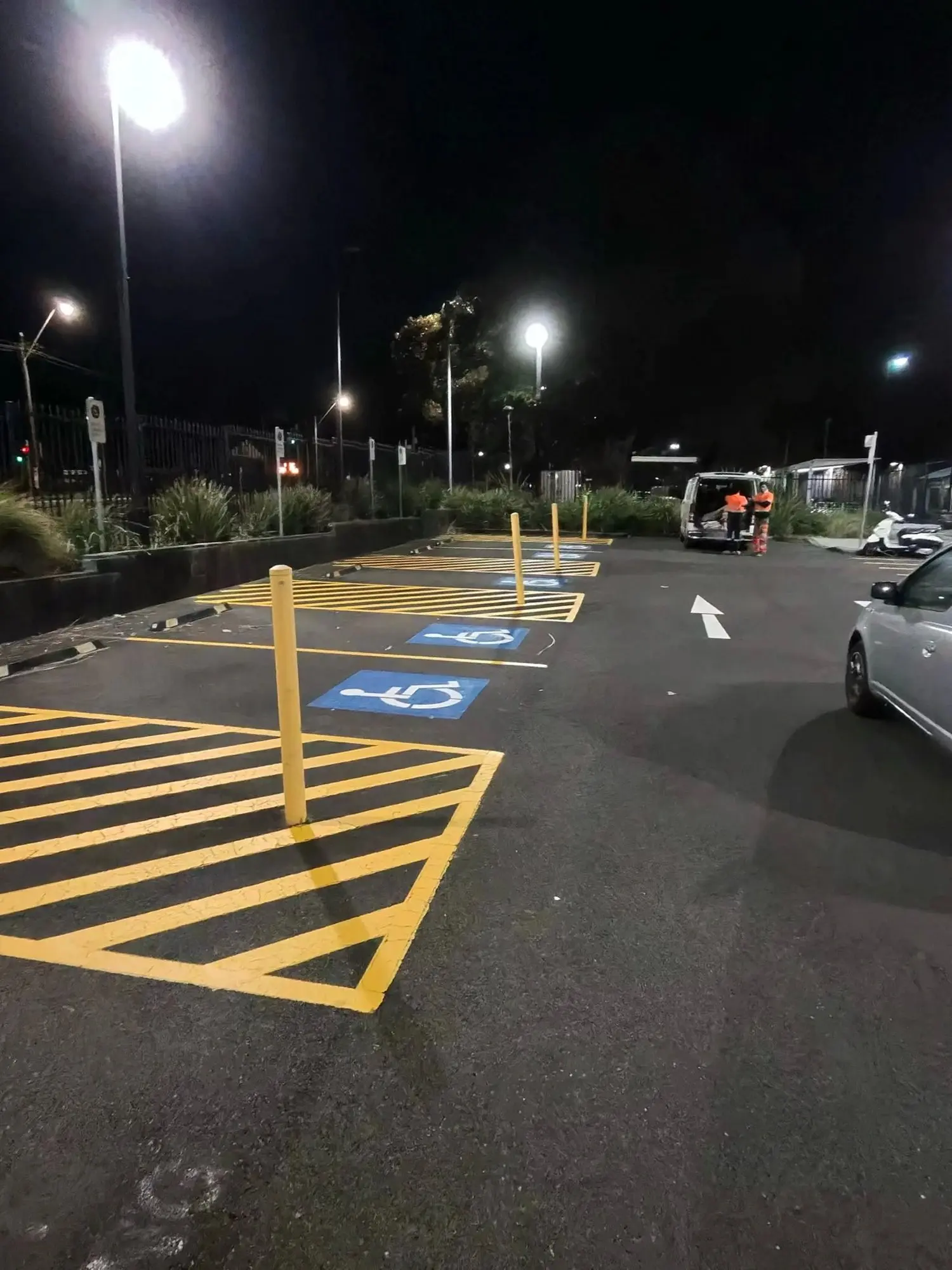 Night works, Sydney: AS2890.6 accessible parking bays with International Symbol of Access stencils, yellow shared-zone hatching and bollards — completed after hours by Speedy Line Marking.